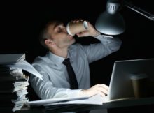 Manager working in office at night and drinking coffee at his workplace
