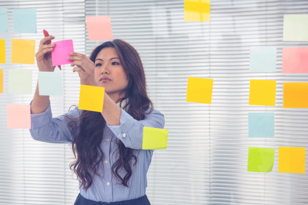 asian-businesswoman-using-sticky-notes-wall-office_107420-951