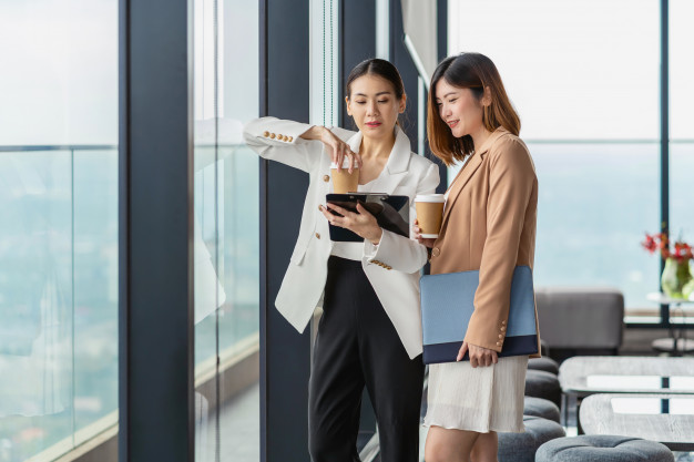 two-asian-businesswomen-talking-during-coffee-break-modern-office-coworking-space_41418-3675