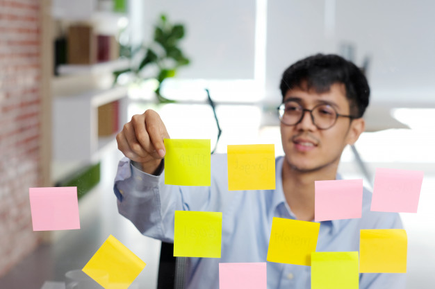 young-asian-man-reading-sticky-note-glass-wall-office-business-brainstorming-creative-ideas-office-lifestyle-success-business_7190-3056