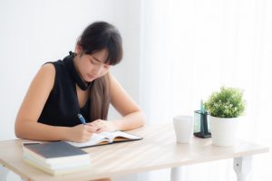 beautiful-young-asian-woman-smiling-sitting-study-learning-writing-notebook-diary-living-room_7192-2154